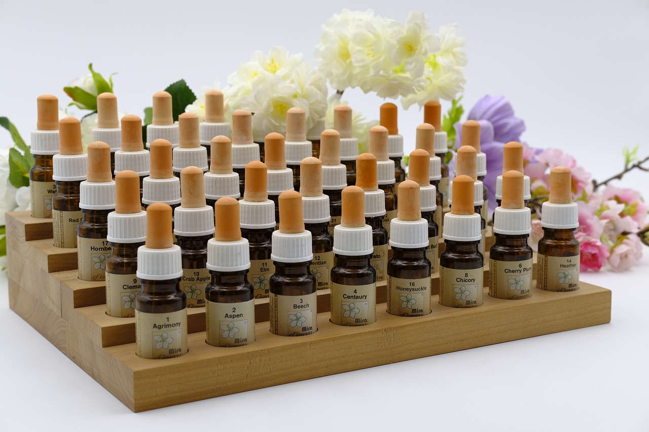 the 38 Bach flower essences on a pedestal for essence bottles, lined up one after the other and labeled, flowers lie in the background