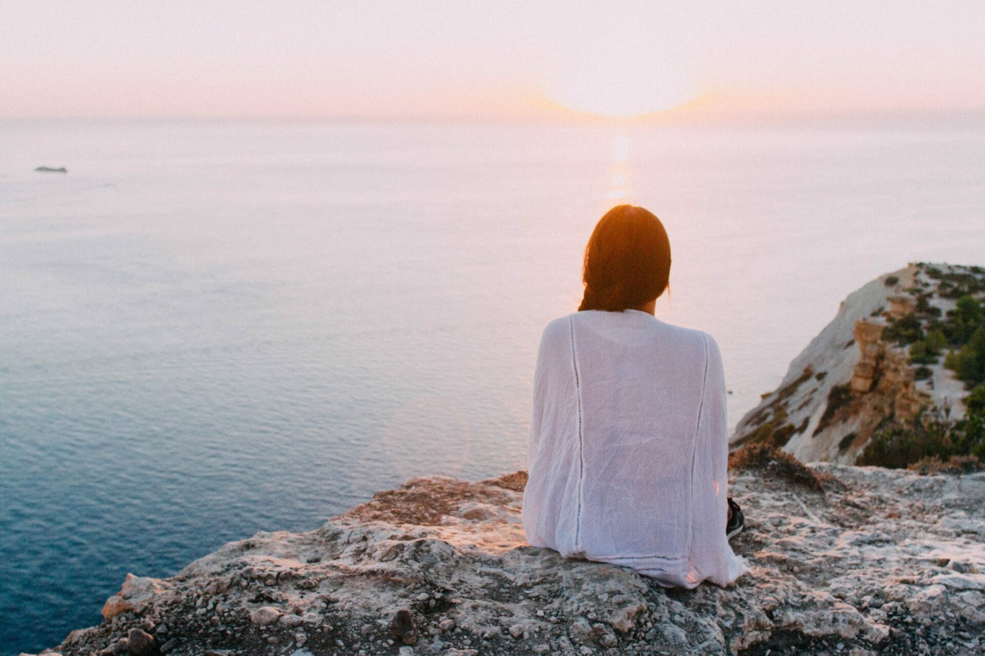 Woman sitting on a rock and looking at the sun