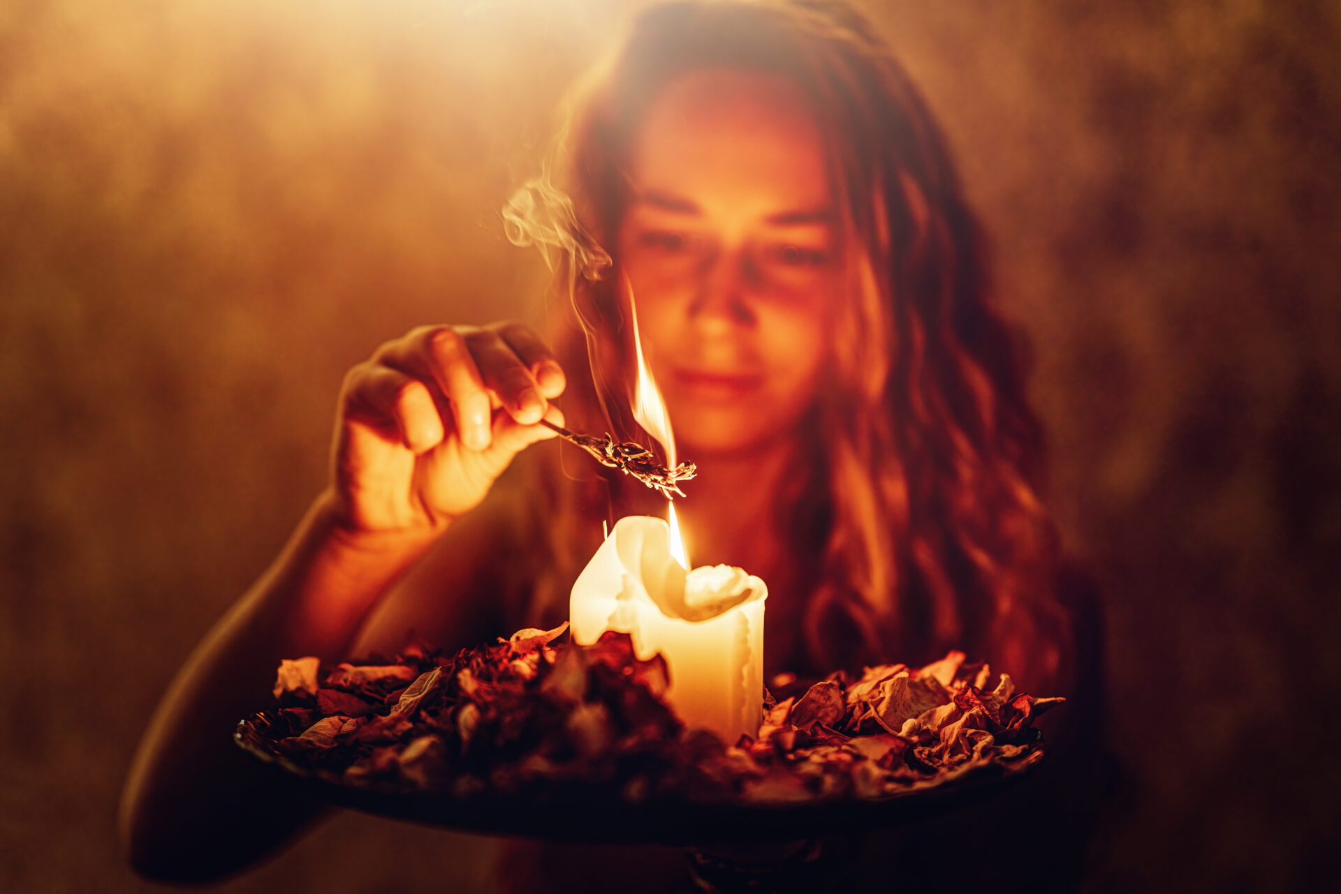 Woman lights a dry plant on a candle.