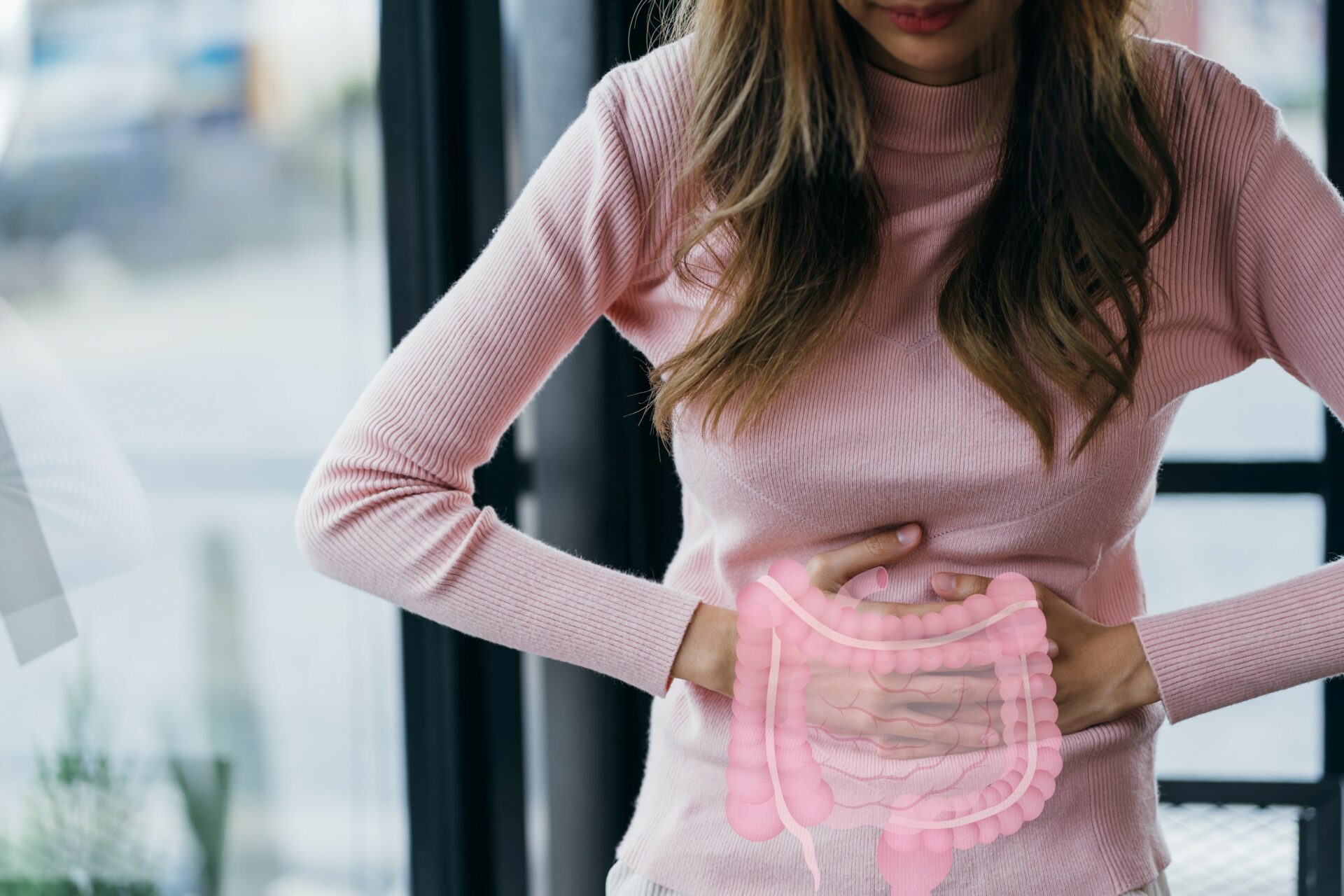 woman stands there holding her stomach in pain. In front of it you can see a pictorial representation of the intestine.