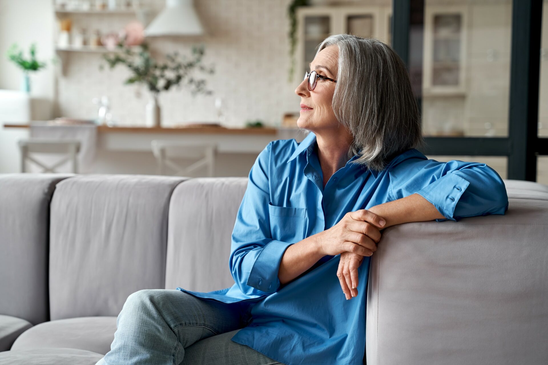 Woman sitting relaxed on a sofa and looking out of the window