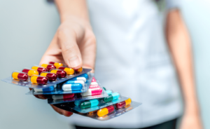 Person hält eine Sammlung an Tabletten und Antibiotika in der Hand.