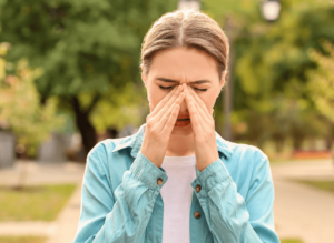 Woman holds her itchy nose. Allergy that can trigger asthma