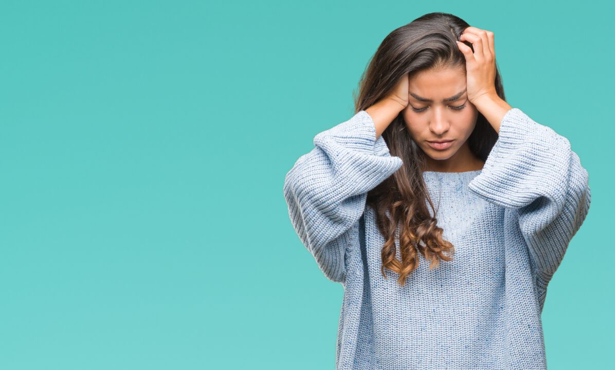 Eine Frau hält sich den Kopf aufgrund von Migräne-Kopfschmerzen
